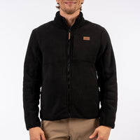 Man wearing a black jacket with a visible brand logo on a white background