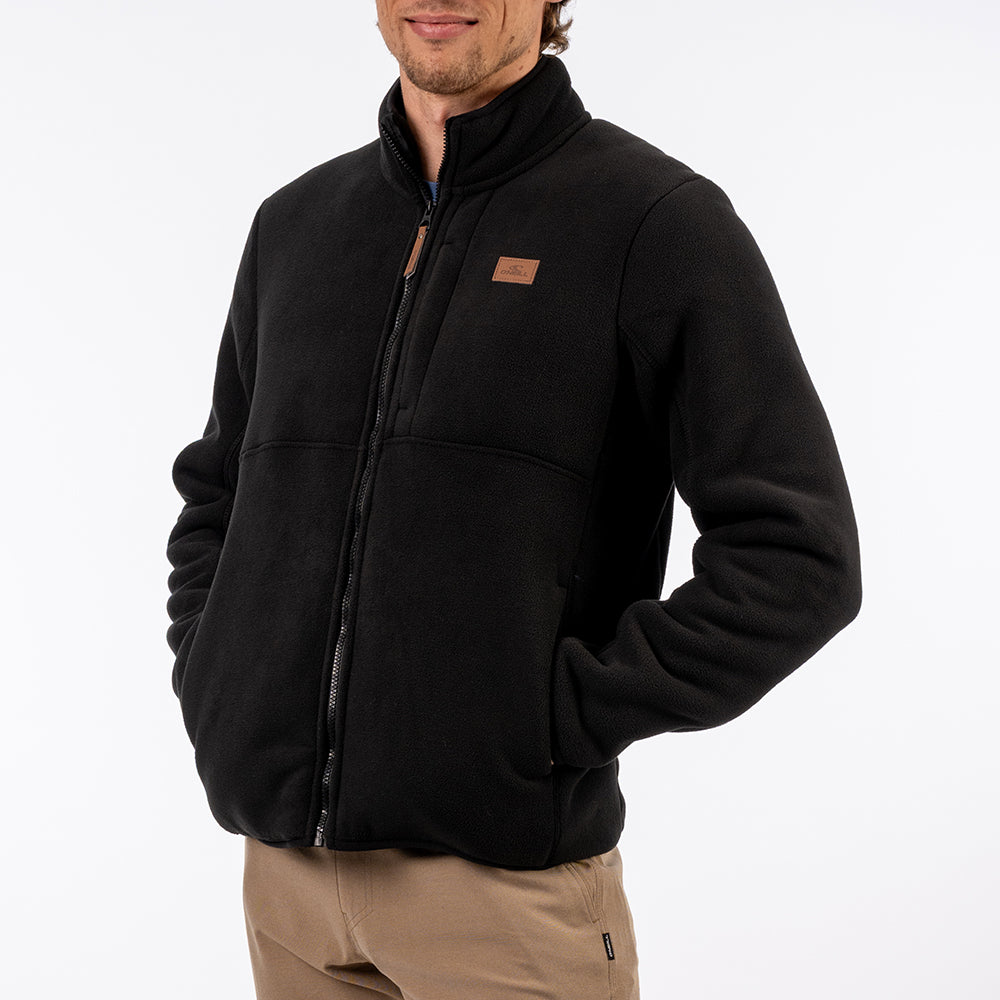Man wearing a black jacket with a visible brand logo on a white background