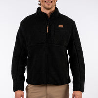Man wearing a black fleece jacket with a brand logo on a white background