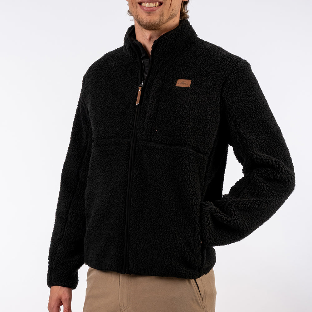 Person wearing a black fleece jacket with a brand logo on a white background