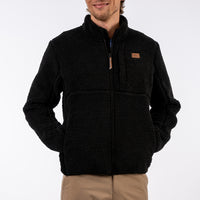 Person wearing a black fleece jacket with a brand logo on a white background