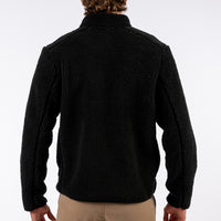 Person wearing a black fleece jacket on a white background
