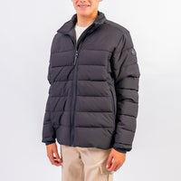 Person wearing a dark gray puffer jacket on a white background