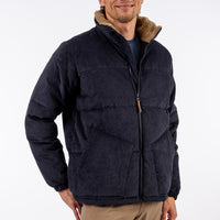 Man wearing a dark blue jacket with brown fur lining on a white background