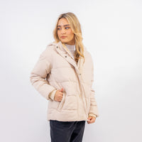 Woman wearing a beige quilted jacket on a white background