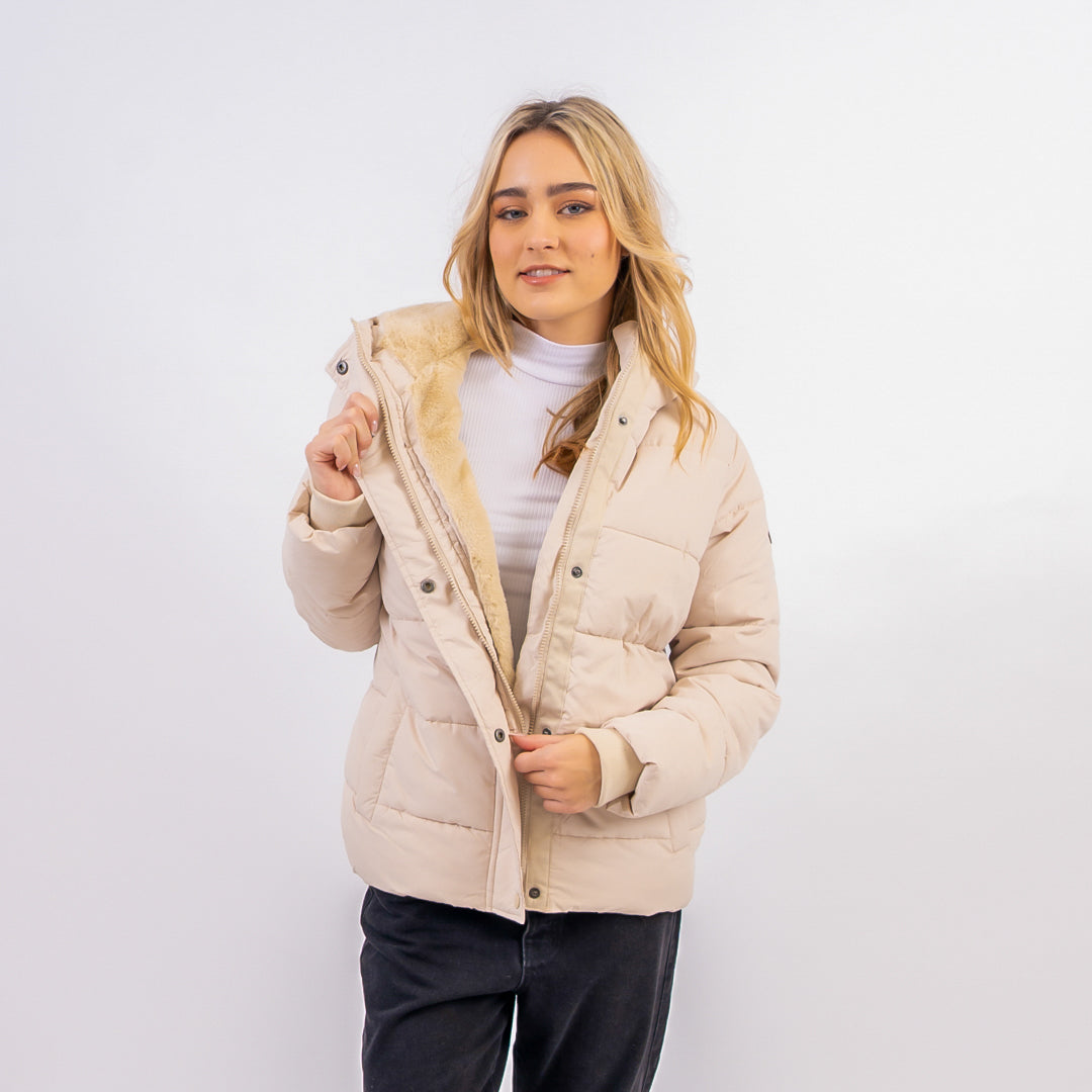Woman wearing a beige quilted jacket on a white background