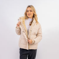 Woman wearing a beige quilted jacket on a white background