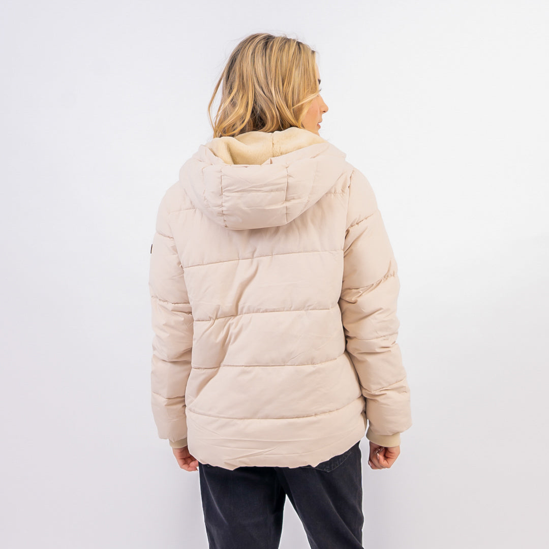 Person wearing a beige puffer jacket with a hood on a white background