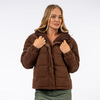 Woman wearing a brown puffer jacket on a white background