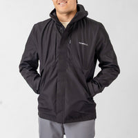 Man wearing a black jacket with a visible brand logo on a light gray background