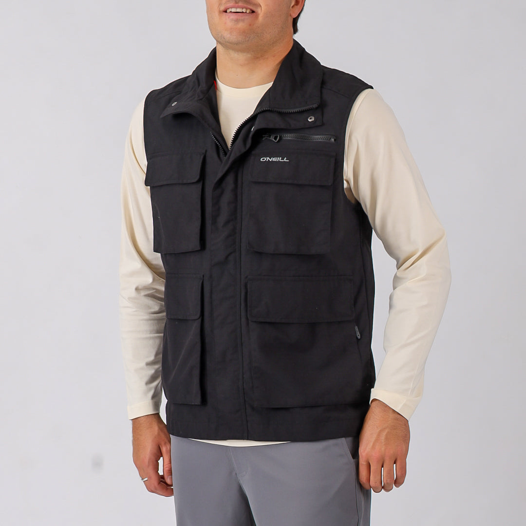 Man wearing a black vest with multiple pockets on a plain background