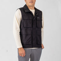 Man wearing a black vest over a white shirt on a light gray background