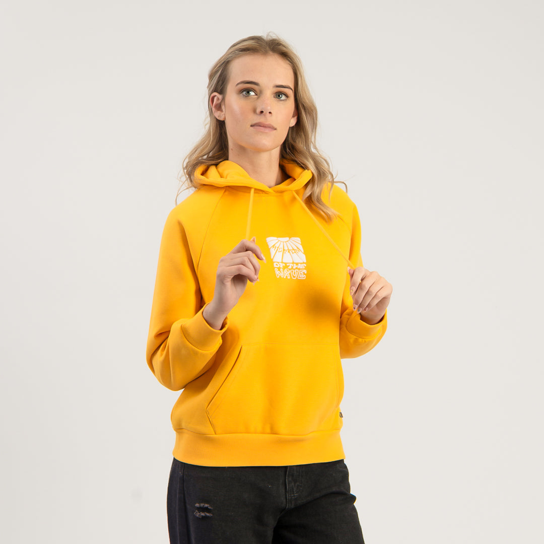 Person wearing a yellow hoodie with a logo on a light gray background