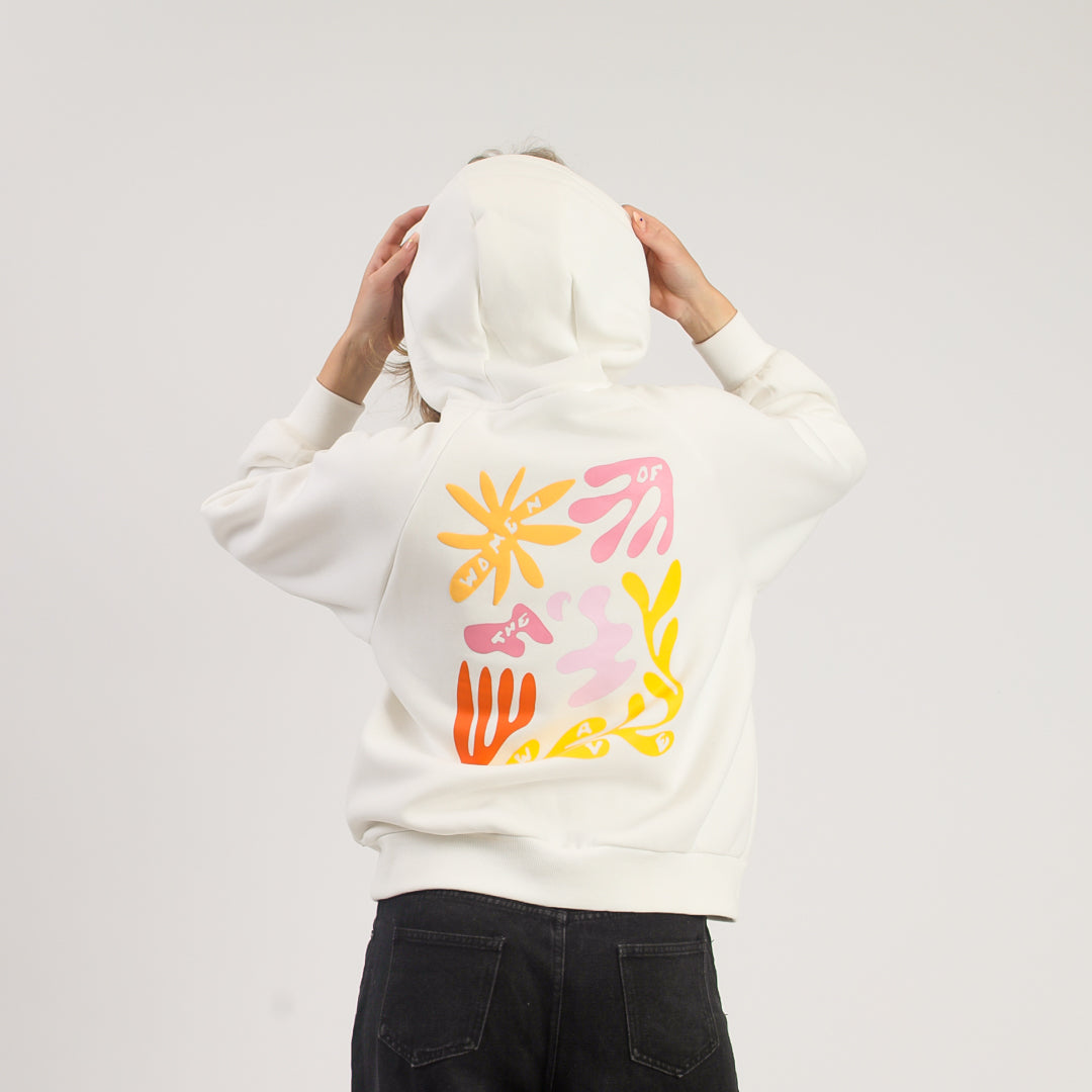 Person wearing a white hoodie with colorful abstract designs on the back against a plain background