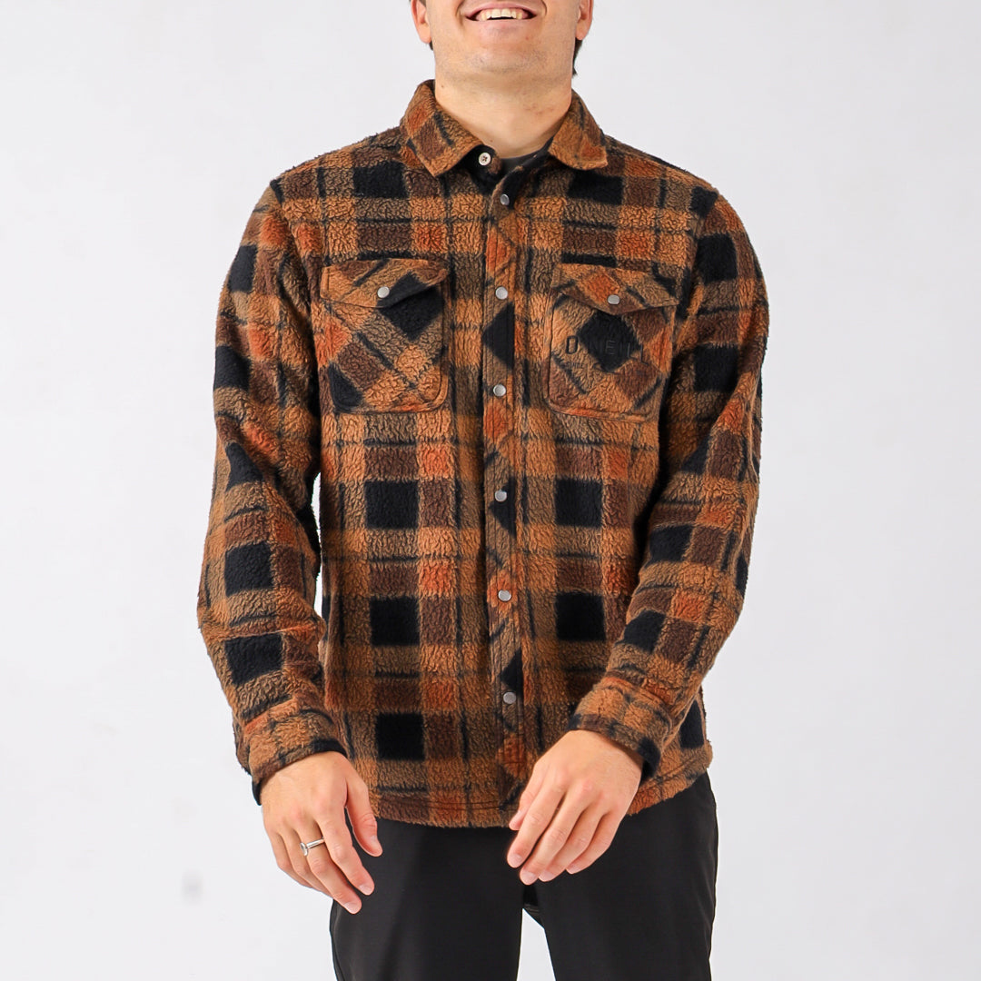 Person wearing a brown and black plaid shirt on a white background