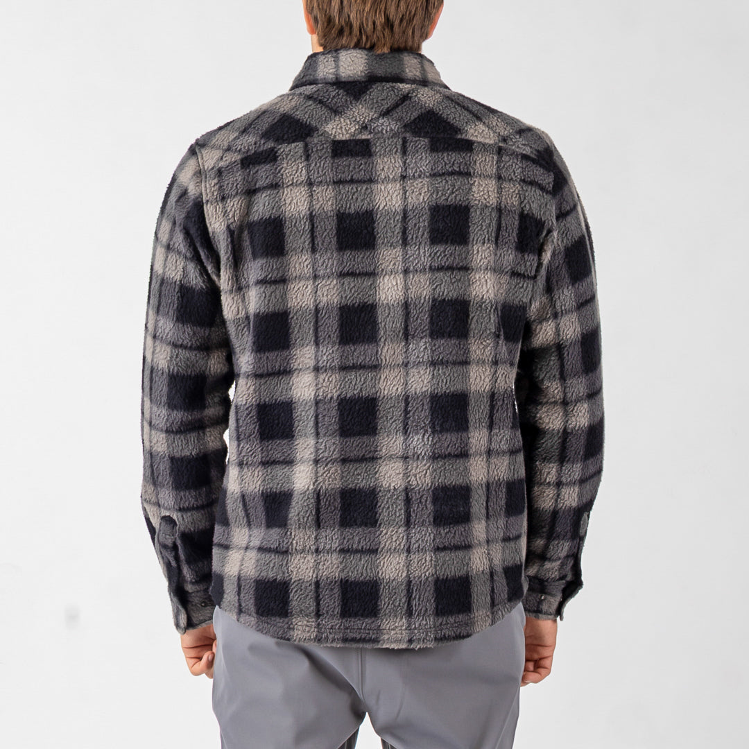 Person wearing a black and gray plaid shirt on a white background