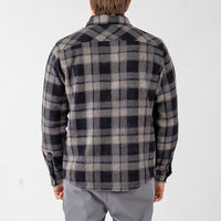 Person wearing a black and gray plaid shirt on a white background