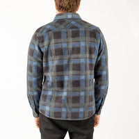 Person wearing a blue and gray plaid shirt on a white background