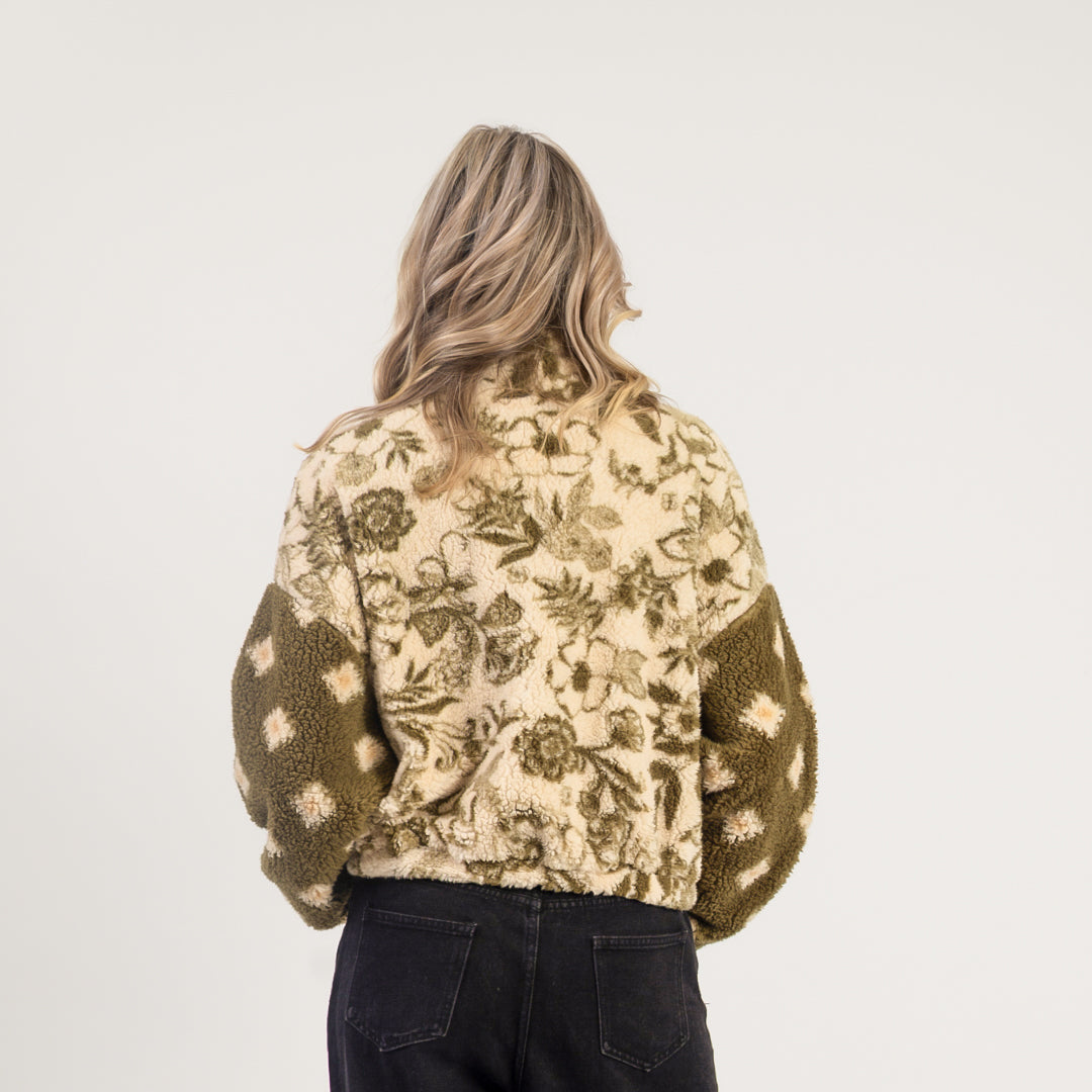 Person wearing a floral patterned jacket with a plain background