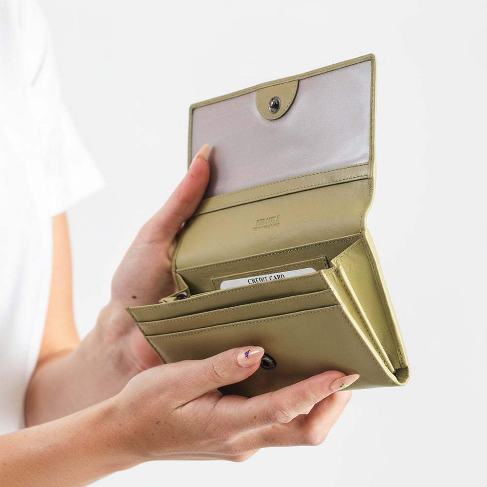 Hand holding a beige wallet with a white background