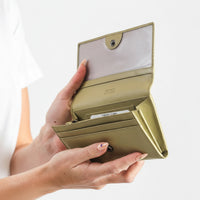 Hand holding a beige wallet with a white background