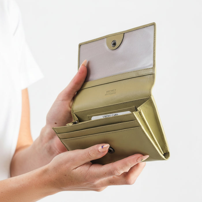 Hand holding a beige wallet with a white background