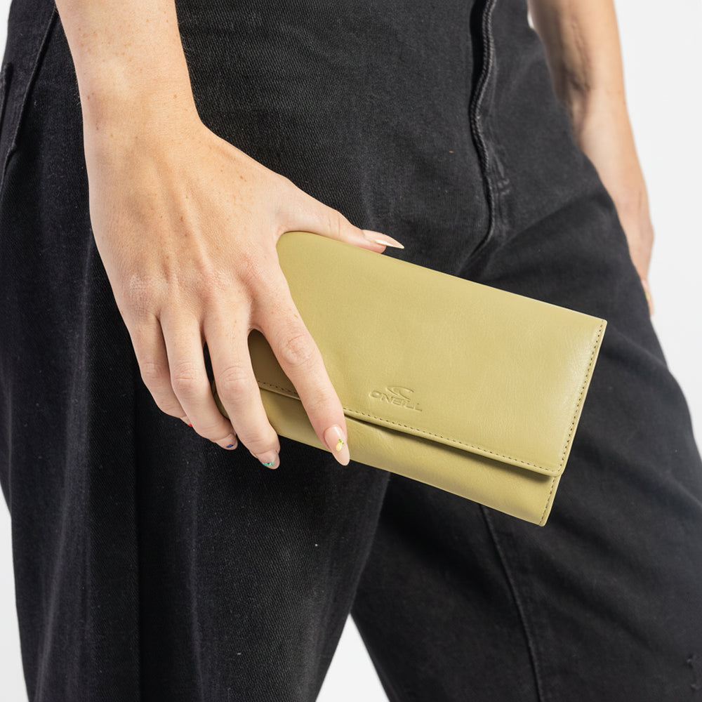 Person holding a beige wallet with a brand logo, wearing black pants.