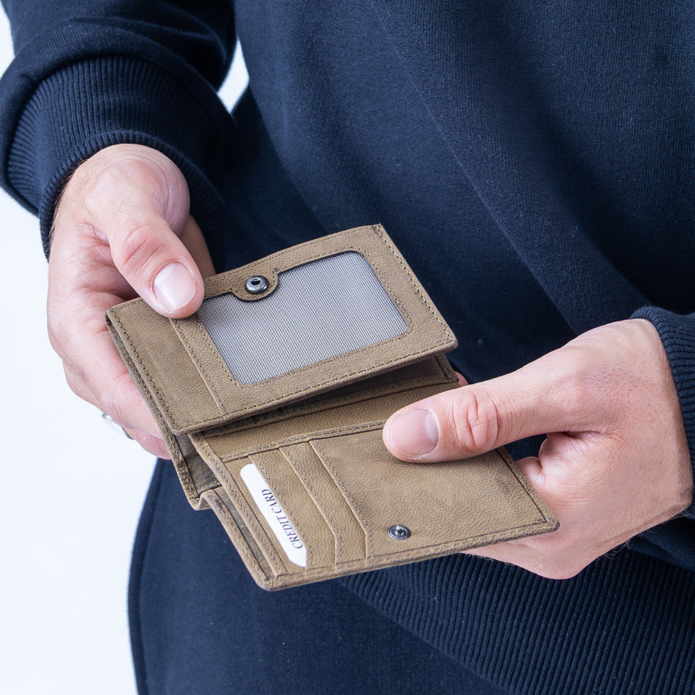 Brown wallet held by a person against a dark background