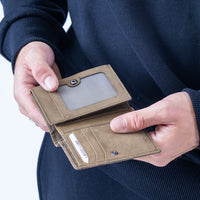 Brown wallet held by a person against a dark background