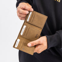 Brown wallet with card slots held by a person wearing a black sweater.