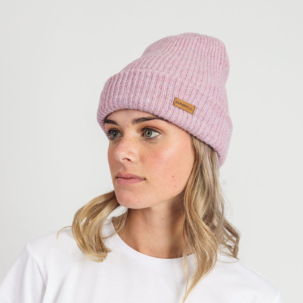 Woman wearing a pink beanie with a brand logo on a white background