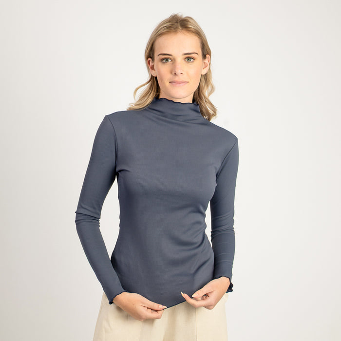 Woman wearing a gray long-sleeve top against a white background