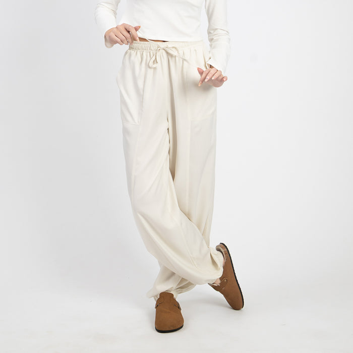 Person wearing white wide-leg pants and brown shoes on a white background