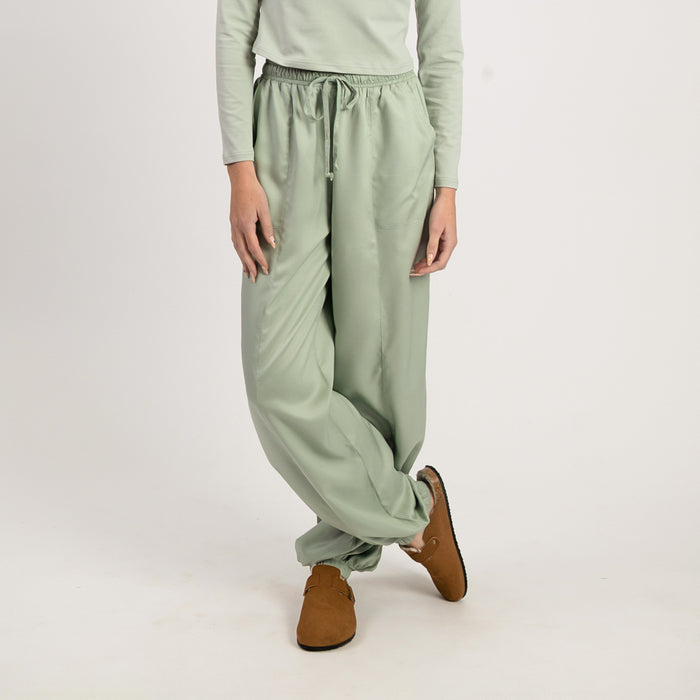 Person wearing light green pants and brown shoes on a white background