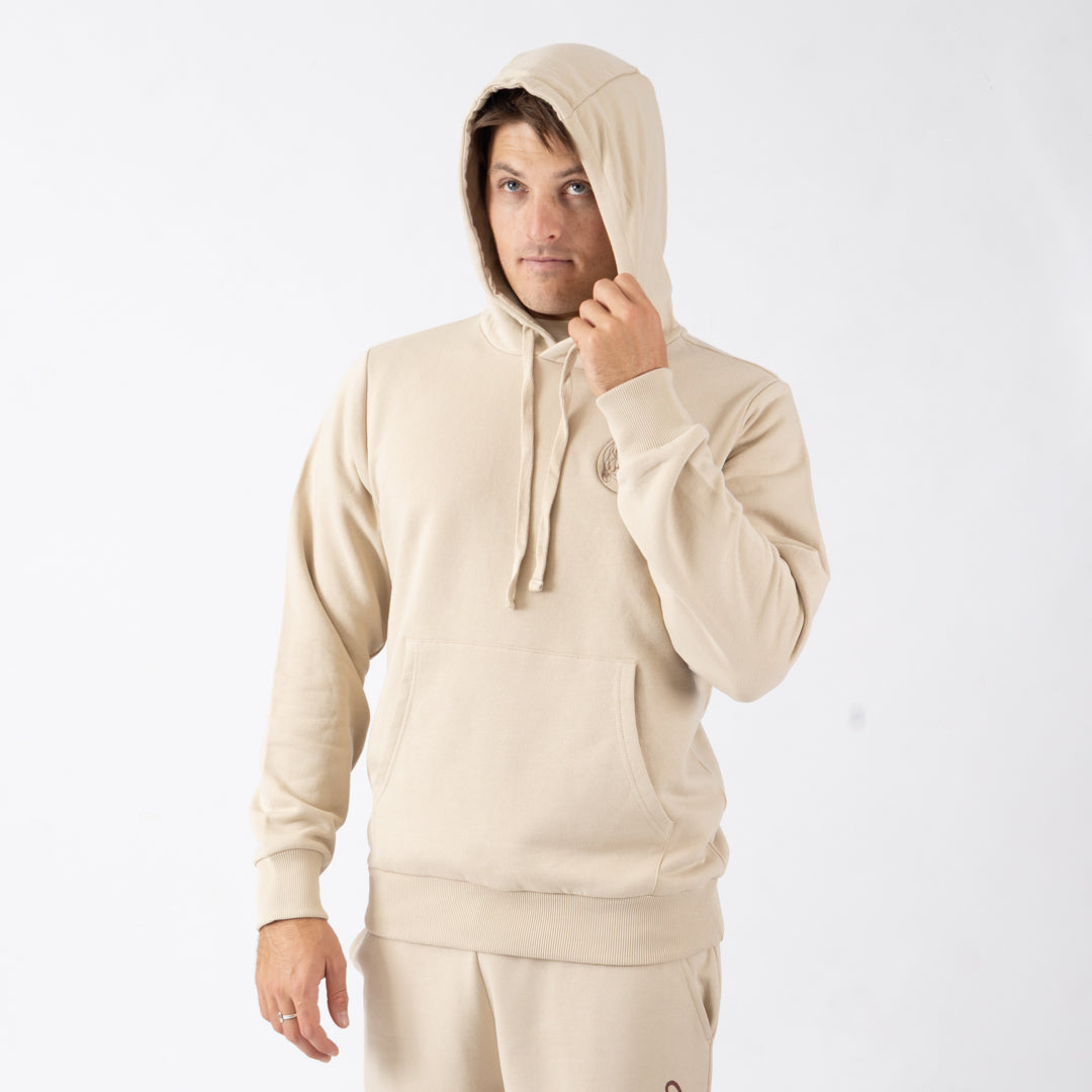 Man wearing a beige hoodie and pants on a white background