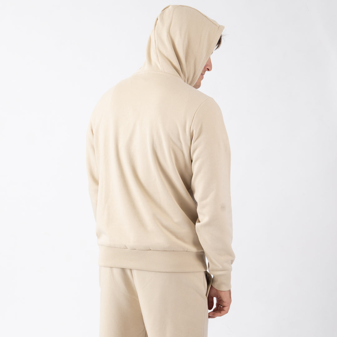 Person wearing a beige tracksuit on a white background