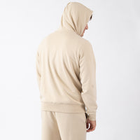 Person wearing a beige tracksuit on a white background