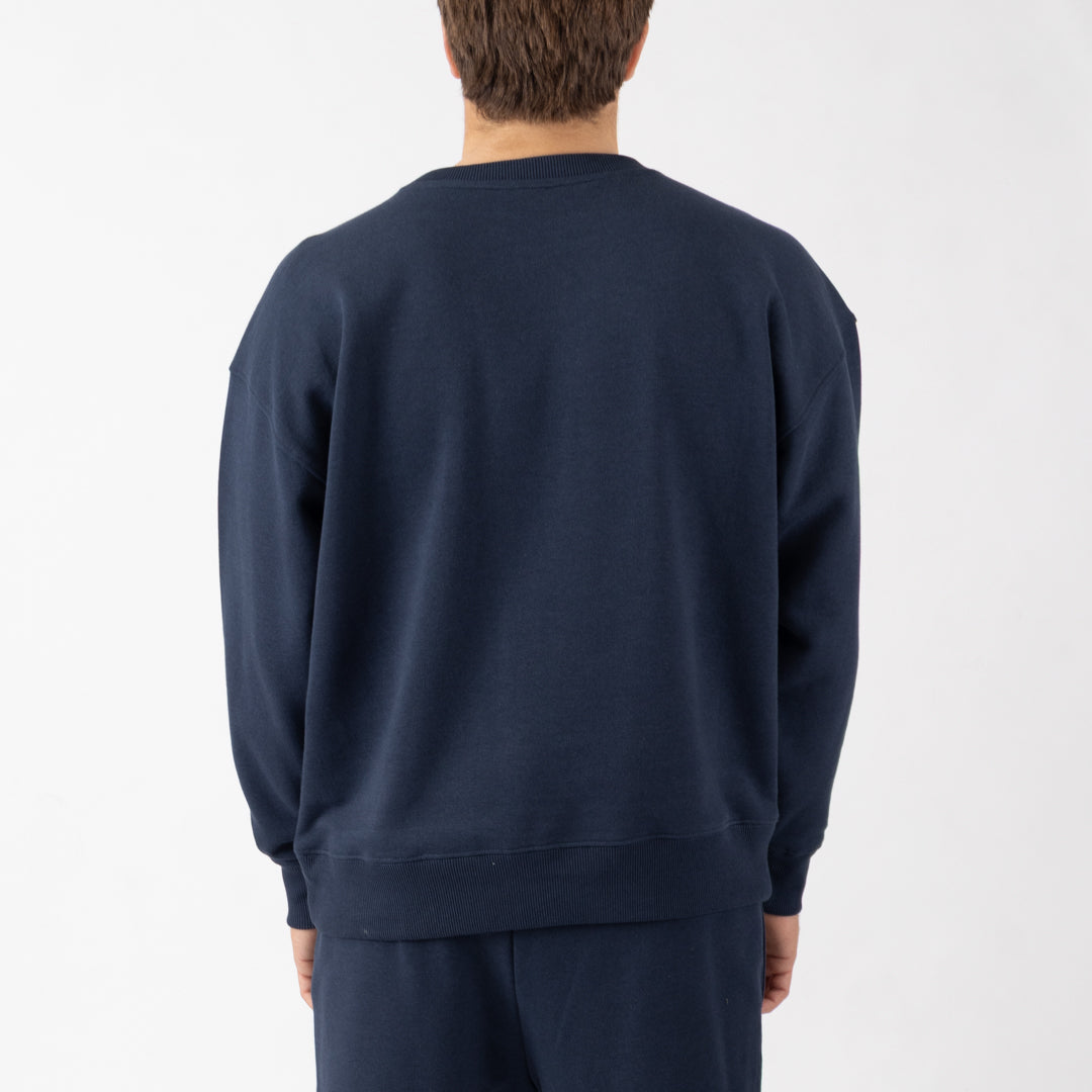 Person wearing a navy blue sweatshirt and pants on a white background