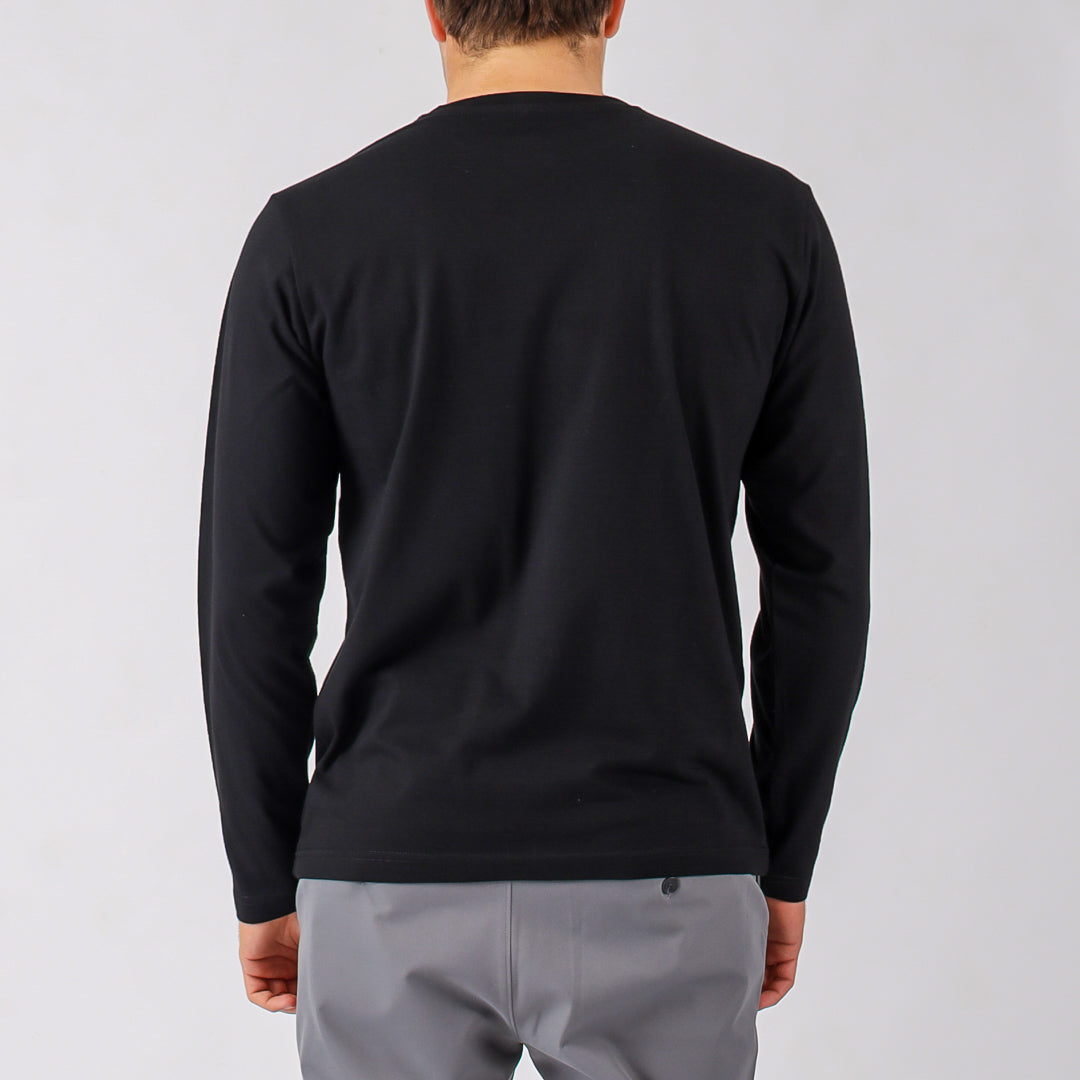 Person wearing a black long-sleeve shirt and gray pants on a light gray background