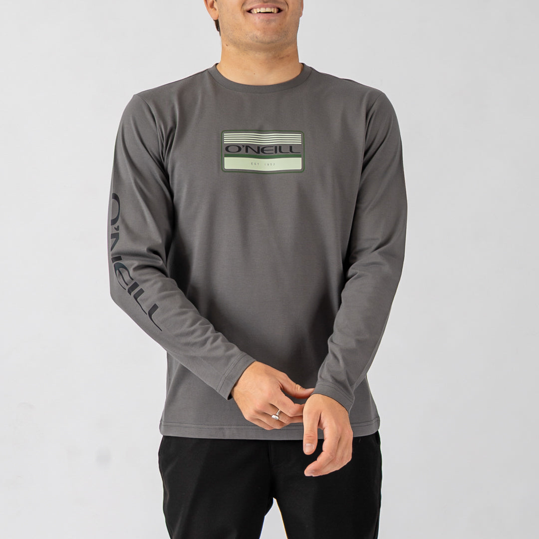 Man wearing a gray long-sleeve shirt with a logo on a light gray background