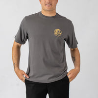 Man wearing a gray t-shirt with a yellow logo on a plain background