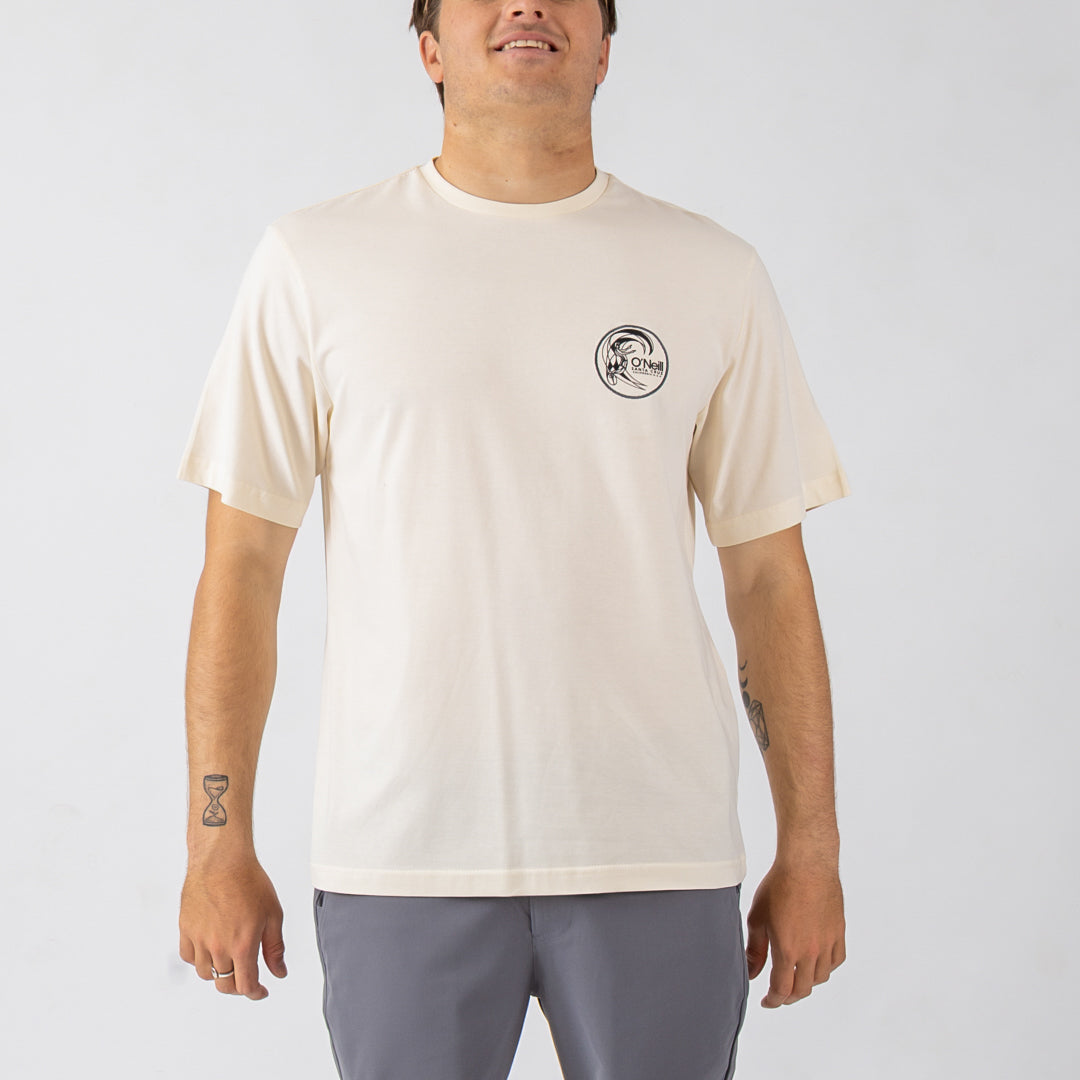 Person wearing a beige t-shirt with a logo on a plain background