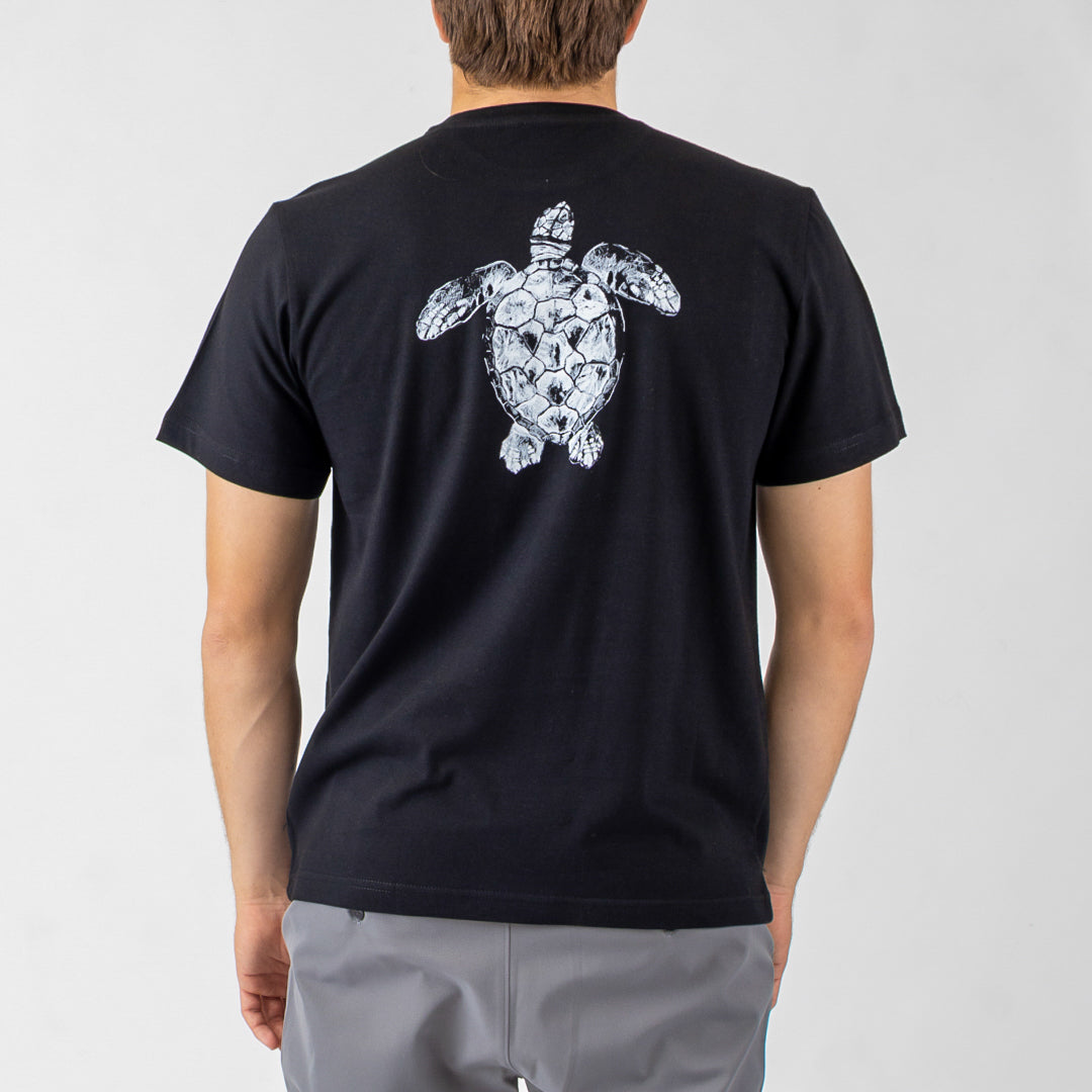 Person wearing a black t-shirt with a white turtle design on the back against a gray background