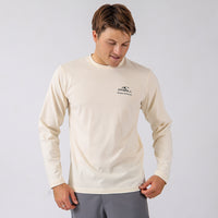 Man wearing a beige long-sleeve shirt with a logo on a light gray background