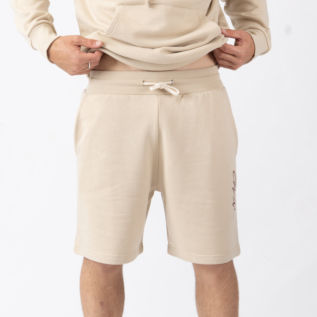 Beige shorts worn by a person on a white background