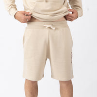 Beige shorts worn by a person on a white background