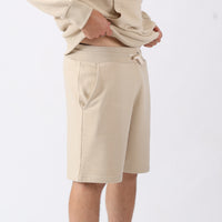 Beige shorts worn by a person on a white background