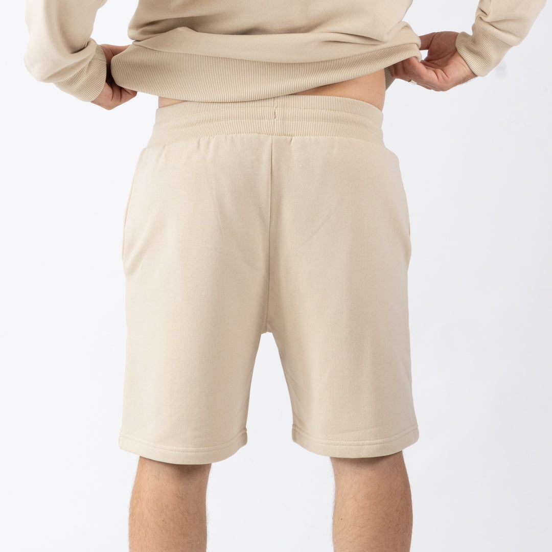 Person wearing beige shorts and a matching top on a white background