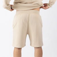 Person wearing beige shorts and a matching top on a white background