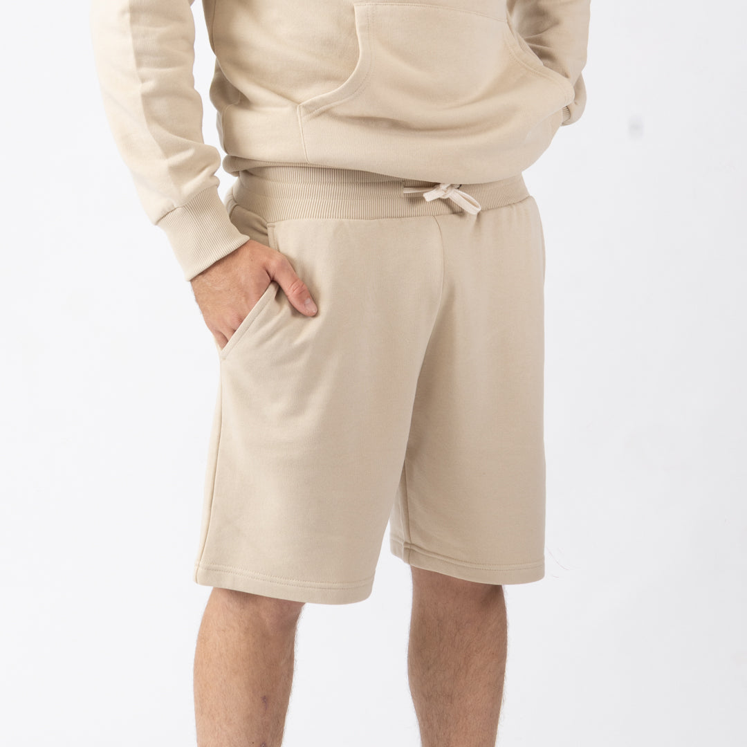 Person wearing beige shorts and a matching hoodie on a white background